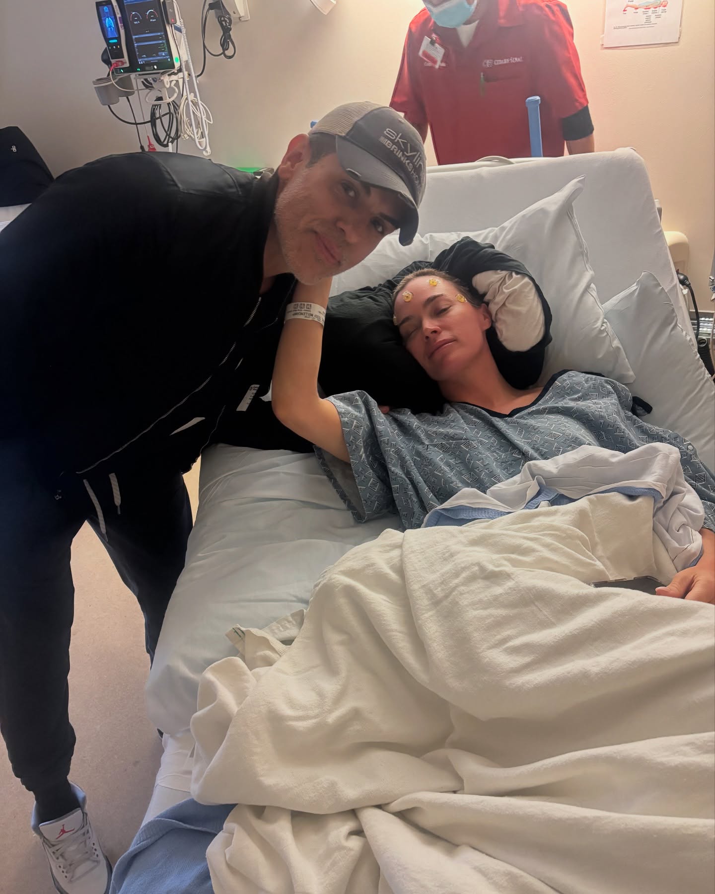 Edwin Arroyave leans over Teddi Mellencamp, who is lying in a hospital bed with electrodes on her head.