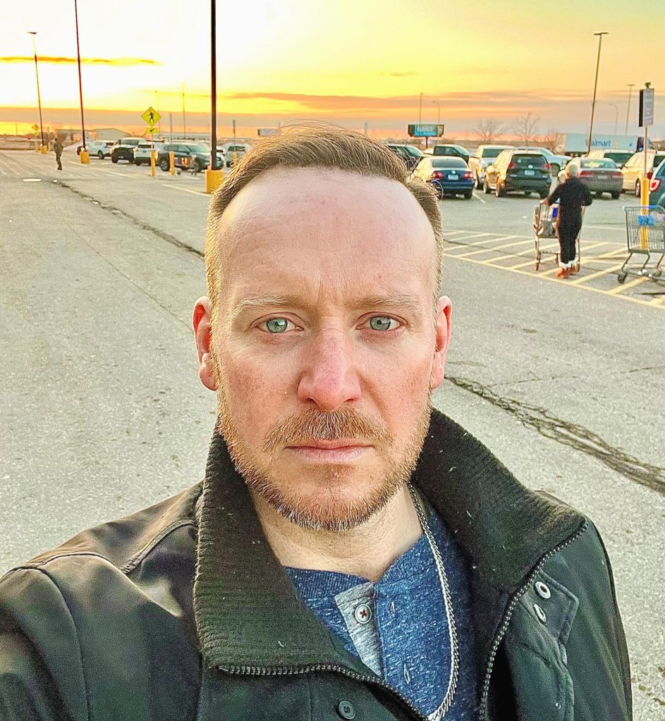Tyler Duckworth in a parking lot with a sunset sky.