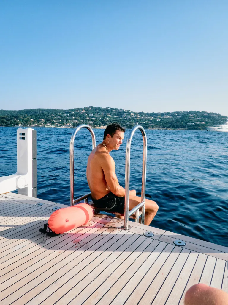 Tom Brady sitting on the edge of a boat, looking out at the water.