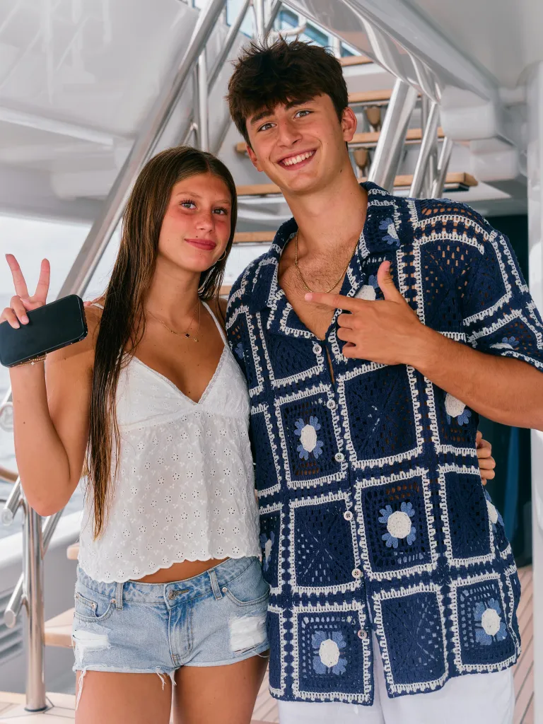 Two teenagers, a girl and a boy, pose on a yacht.