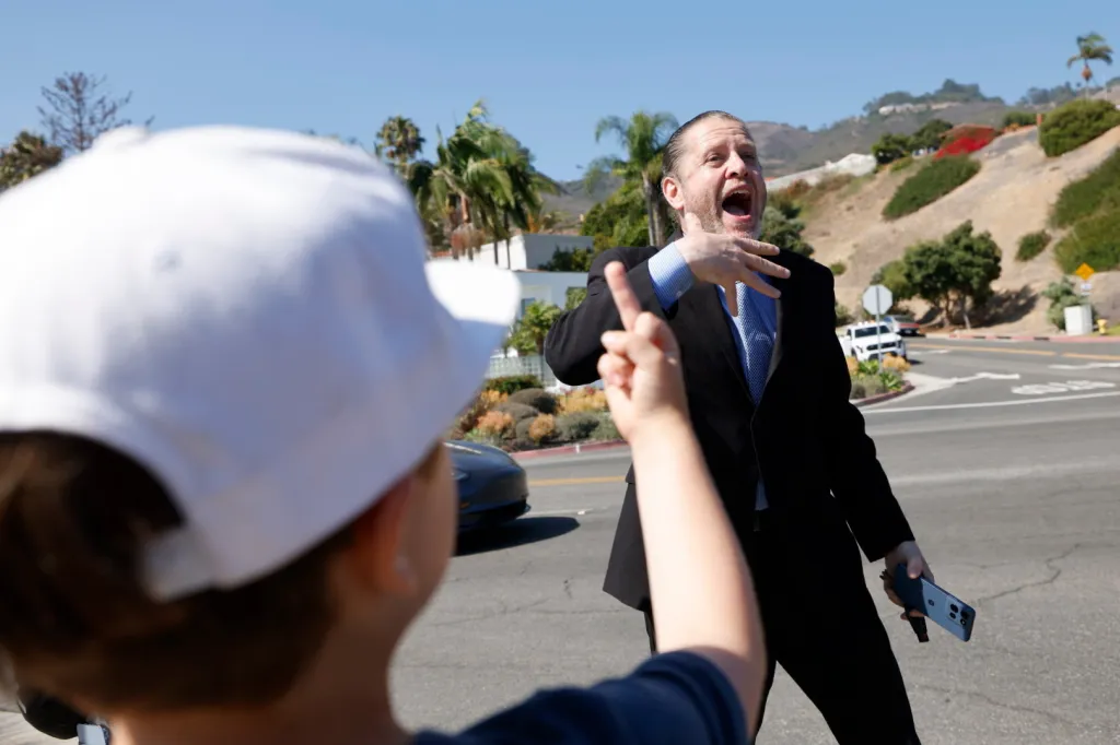 A man in a suit yells at a child pointing at him, during a clash between Trump supporters and protesters.