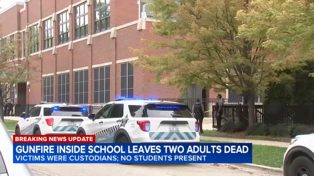 Police vehicles at an elementary school with an on-screen news update about two custodians found shot to death.