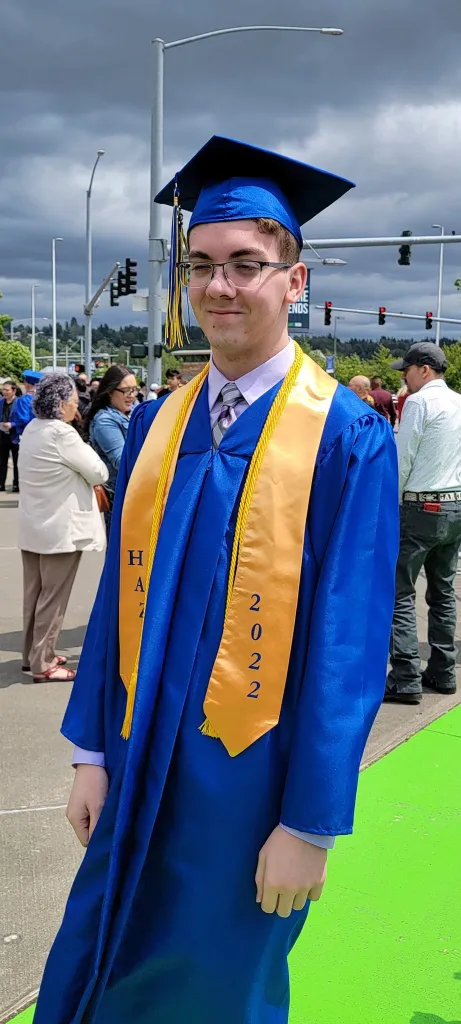 Tyler Sorensen in a blue graduation gown with a gold stole that reads "2022".