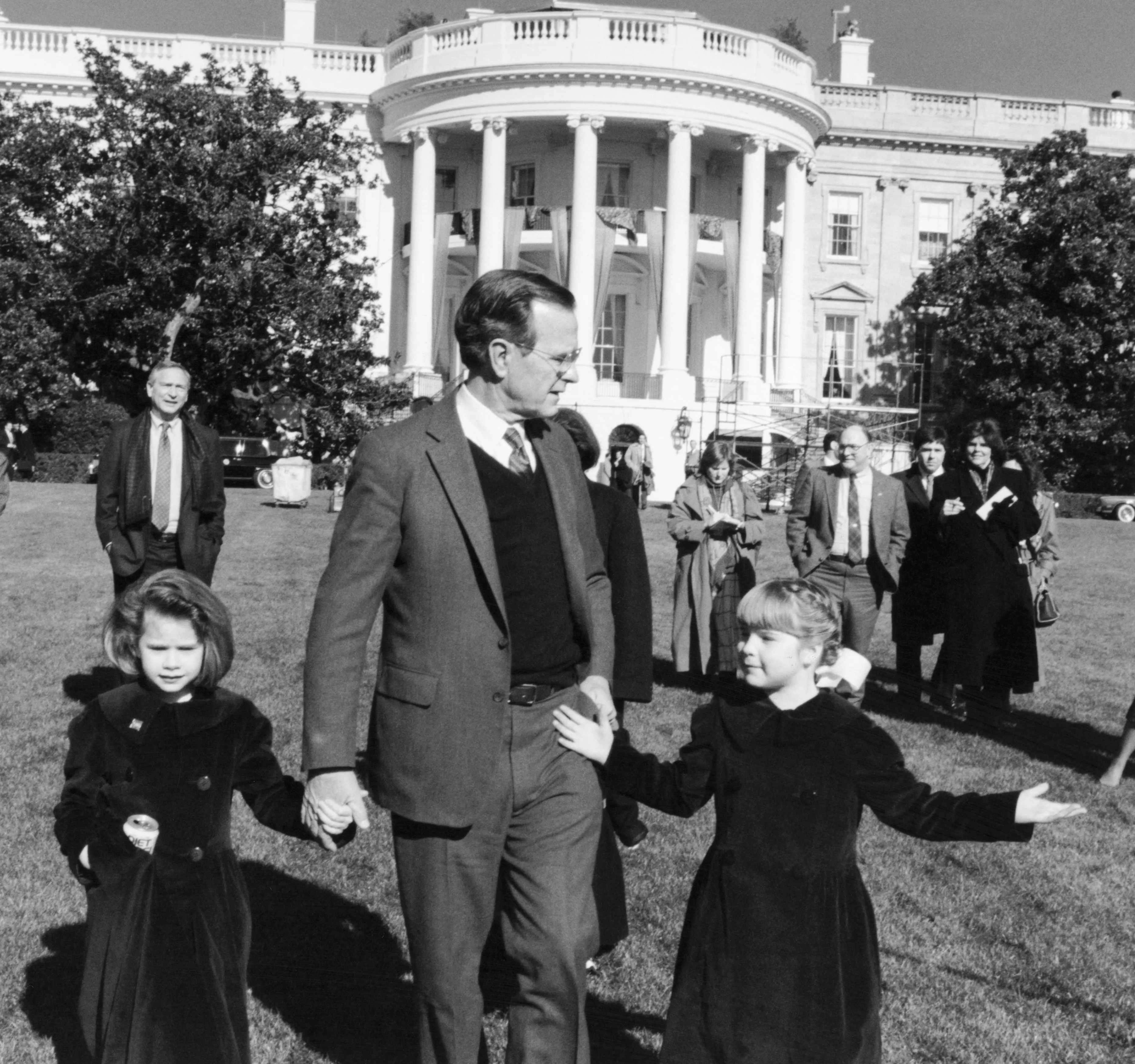 George H.W. Bush holds hands with his granddaughters, Barbara and Jenna, on the south lawn of the White House.