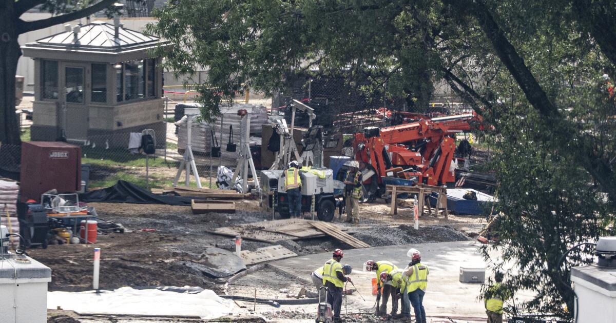 Crews remove the granite seal on the White House helipad, signaling potential project delays