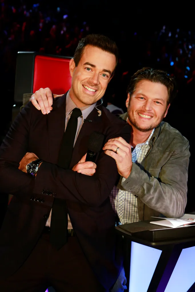 Carson Daly and Blake Shelton smiling with Daly holding a microphone.