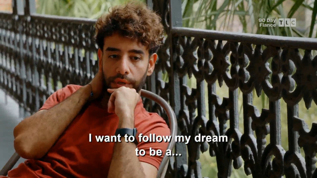A man with curly brown hair and a beard sits on a balcony, with the caption "I want to follow my dream to be a..."