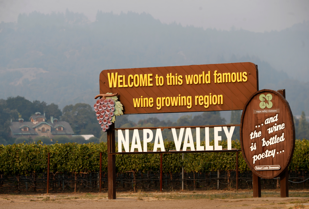 "Welcome to Napa Valley" sign along Highway 29 with smoke from the Glass Fire in the hills.