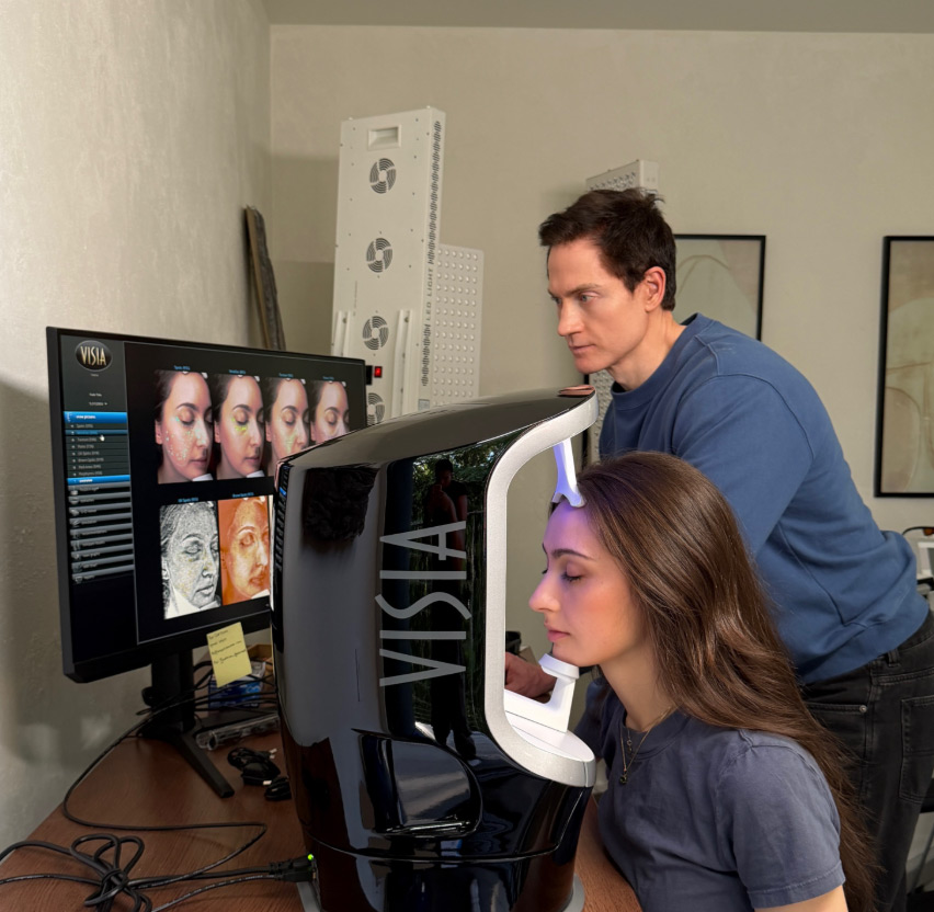 Bryan Johnson observes Kate Tolo undergoing a skin analysis with a VISIA device.