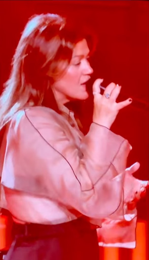 Kelly Clarkson performing in Las Vegas, singing into a microphone.
