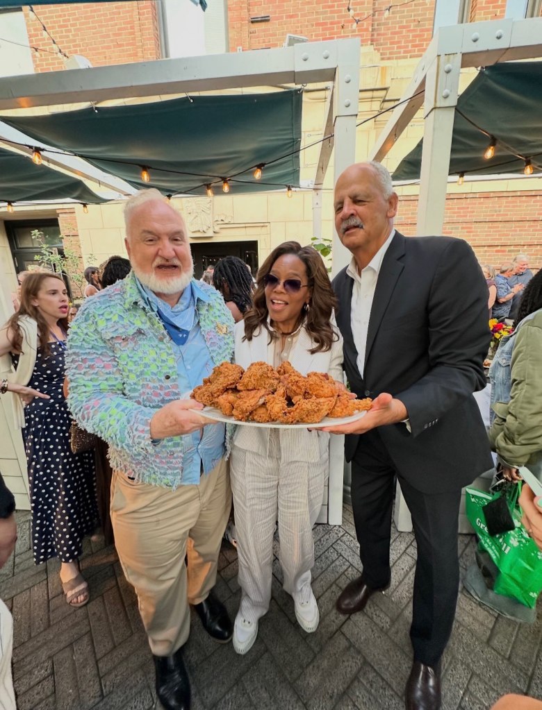 Chef Art Smith, Oprah, and Stedman Graham holding a platter of fried chicken.