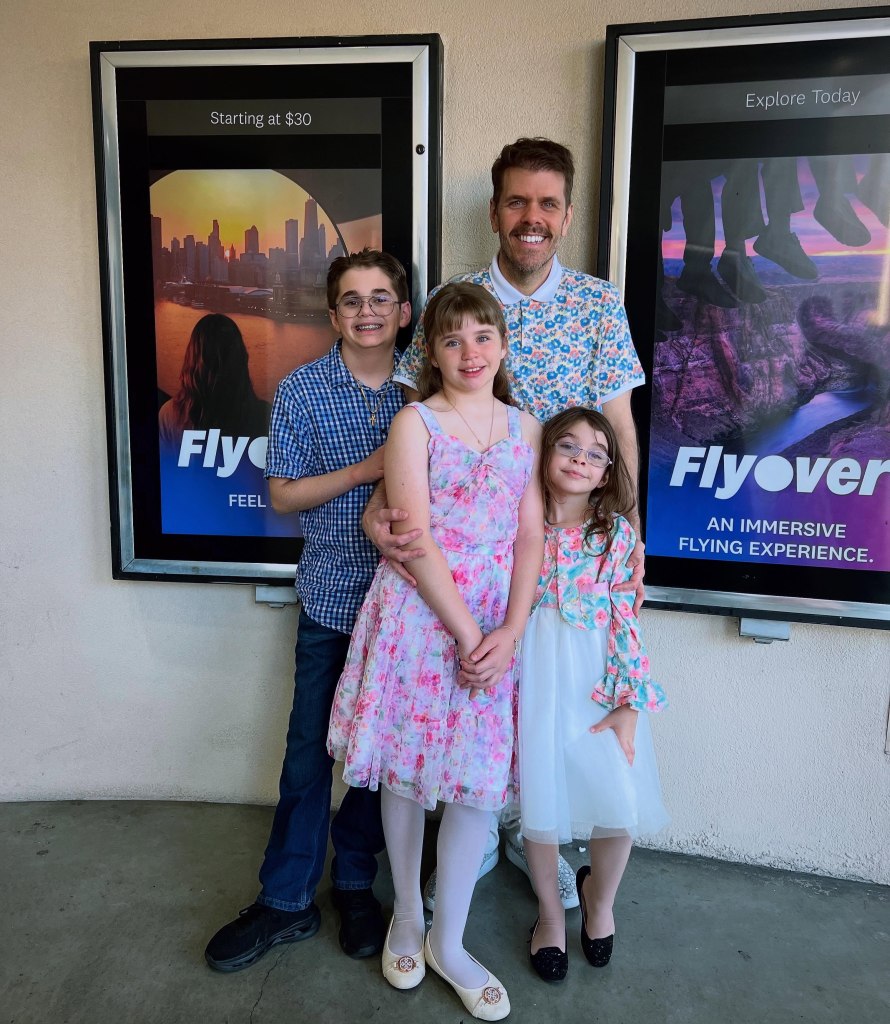 Perez Hilton poses with his three children in front of "Flyover" experience posters.
