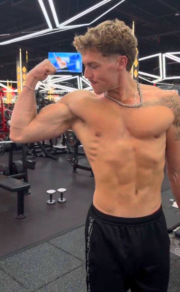 A man in a gym flexing his bicep.