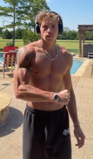A man flexing his bicep next to a pool.