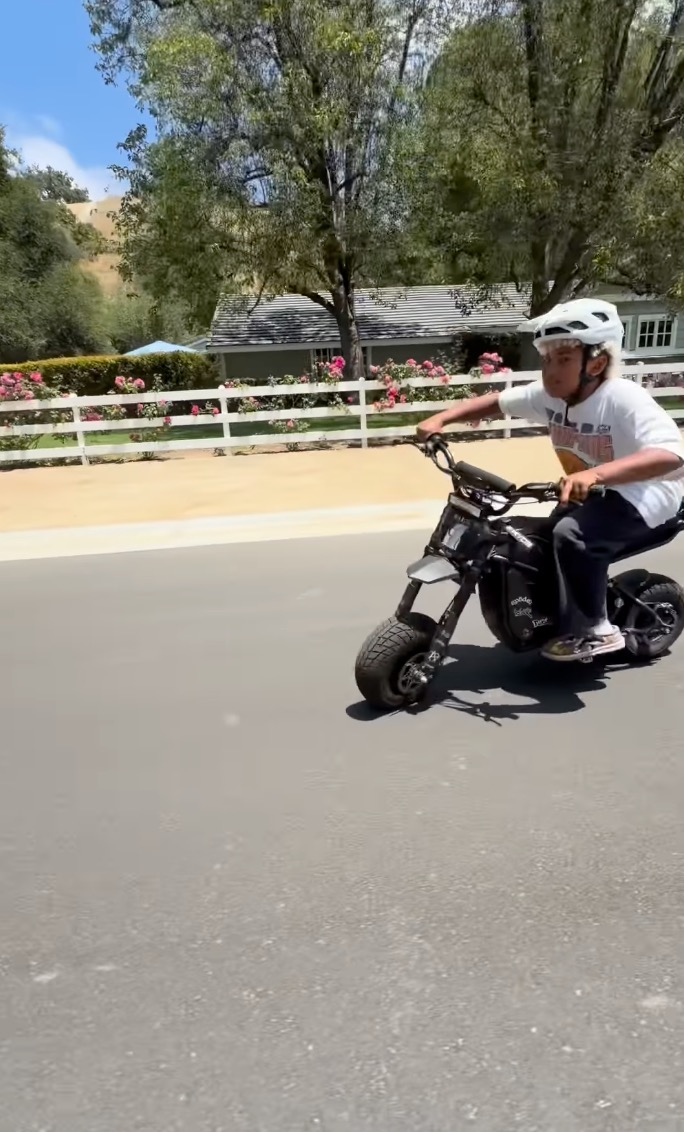 Saint West riding a small motorcycle on the road.