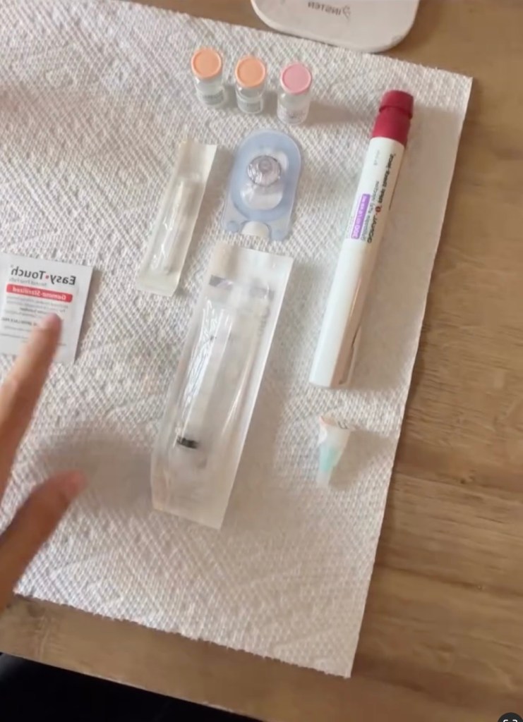Egg-freezing medical supplies including vials, syringes, and an injection pen laid out on a paper towel.
