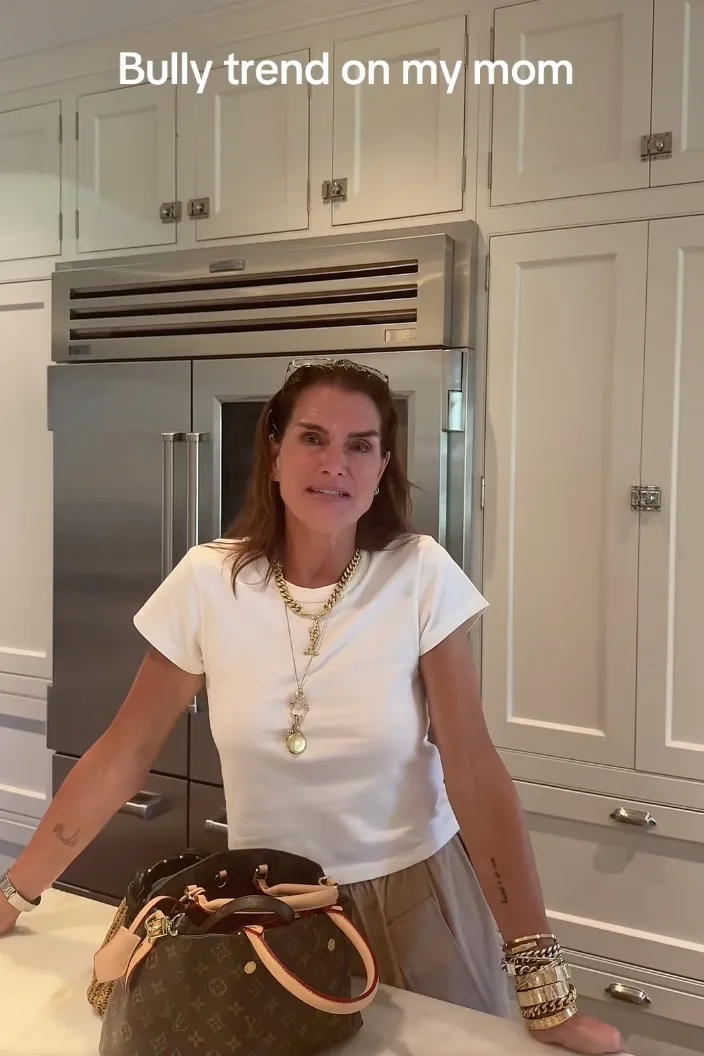 Brooke Shields standing in a kitchen with a Louis Vuitton bag on the counter.