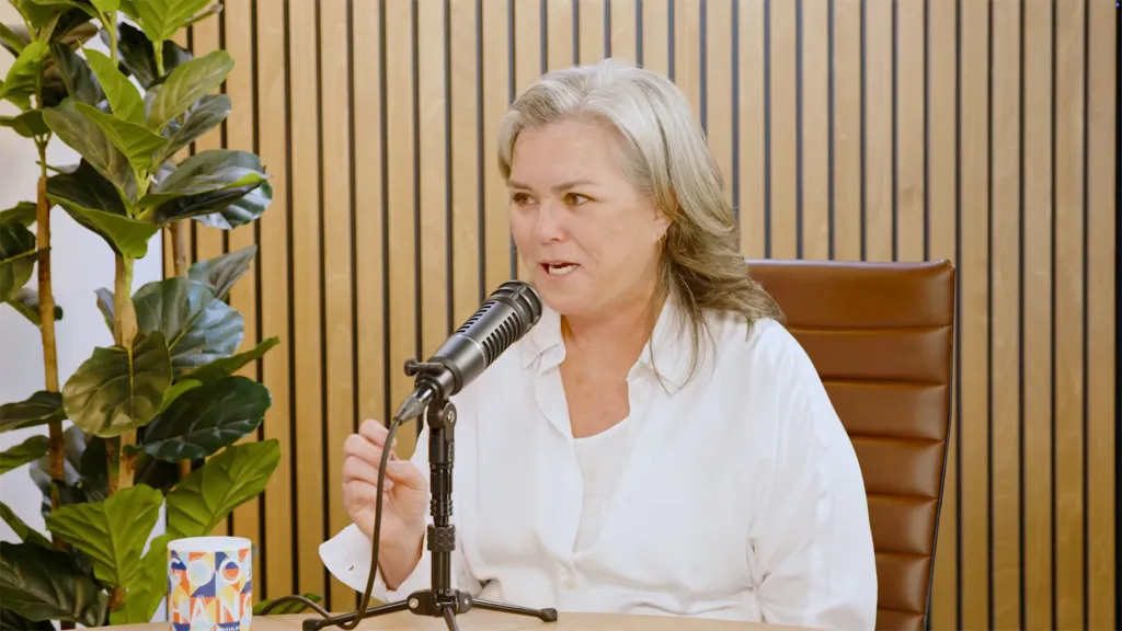 Rosie O'Donnell speaking into a microphone on a podcast.